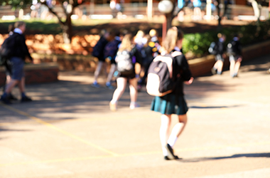 deliberate heavy blur of school students in uniform walking in the yard playground. blurred school kids in the yard. Backpacks outdoor view of buildings and classes.
