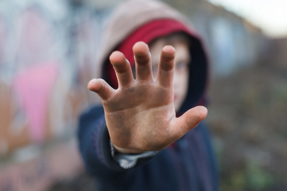 dramatic portrait of a little homeless boy, dirty hand